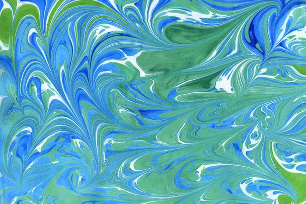 Streszczenie ręcznie robionego tła w technice ebru. Powierzchnia papieru z nadrukiem farb na wodzie. Niebieskie loki, fale i plamy o różnych kształtach i rozmiarach. Unikalna ilustracja sztuki - Zdjęcie, obraz