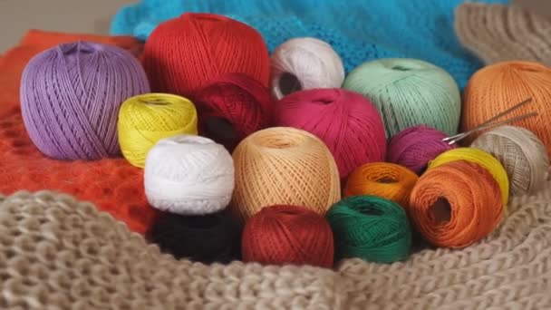 Bolas multicoloridas de fios e agulhas de tricô de metal no fundo de coisas tricotadas. Rotação - Filmagem, Vídeo
