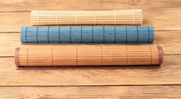 Three rolled up bamboo food mats on a wooden background. Copy space. Close up. - Foto, Bild