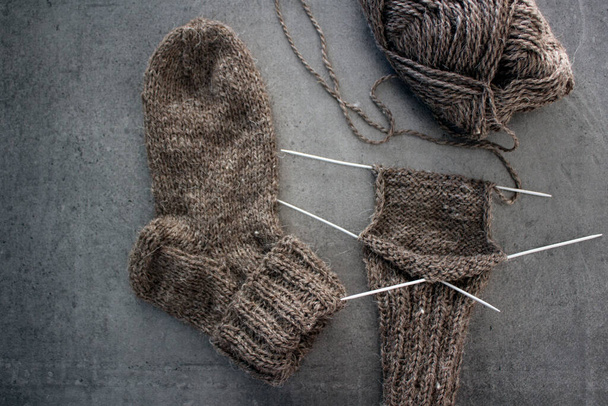 Braune Socken von Hand aus Schafwolle. Foto von oben mit gestrickten Socken, Nadeln und Knäueln aus warmem Garn. Winterliches Hobbykonzept. - Foto, Bild