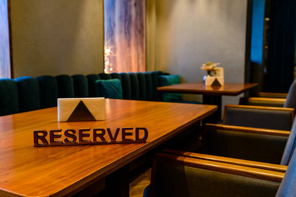A modern idea for a reserved table with the inscription Reservation of your place. Idea restaurants the inscription reserved on a wooden table in a cafe - 写真・画像