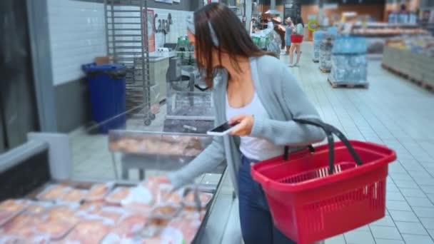 женщина сканирует контейнер с сырой куриной грудью в супермаркете - Кадры, видео