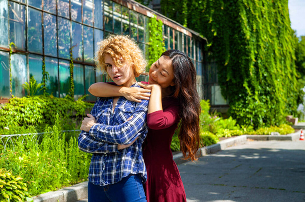 Deux jeunes filles multinationales heureuses s'embrassent dans un parc d'été - Photo, image