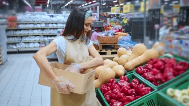 veselý merchandiser sbírání zeleniny v krabici při chůzi v supermarketu - Záběry, video