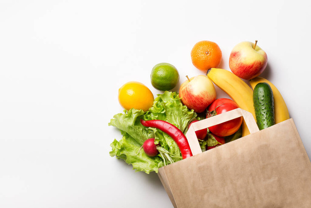 Paper bag with vegetables and fruits on a white background. Online ordering from a grocery store. The concept of proper nutrition. Food delivery. - Fotografie, Obrázek