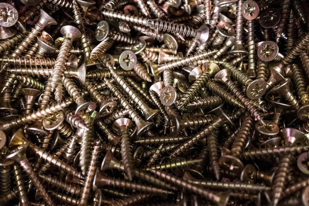 Pile of pozidriv head type screws, with a blurred background. - Fotó, kép