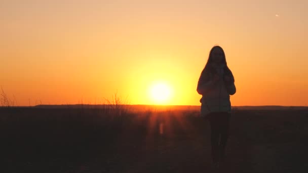Een meidenreiziger loopt met een rugzak op haar rug en glimlacht bij zonsondergang in de lucht. Een tiener op kampeervakantie. Jeugd op zoek naar avontuur van 's ochtends tot' s morgens vroeg. Liefde voor de - Video