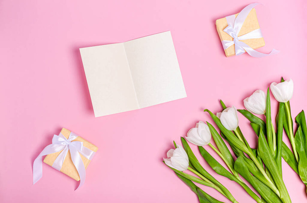 Bouquet of white tulips with a greeting card and gift boxes on a pink background. Spring concept, flat lay, copy space. Banner. View from above. - Foto, Imagem