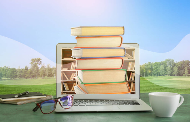 Moderne laptop met boeken op tafel in het park. Concept van online bibliotheek - Foto, afbeelding