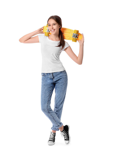 Beautiful young woman with skateboard on white background - 写真・画像