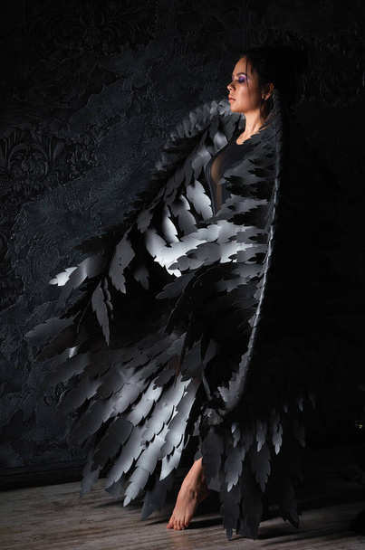 κορίτσι με μαύρα φτερά αγγέλου σε σκοτεινό δωμάτιο. - Φωτογραφία, εικόνα
