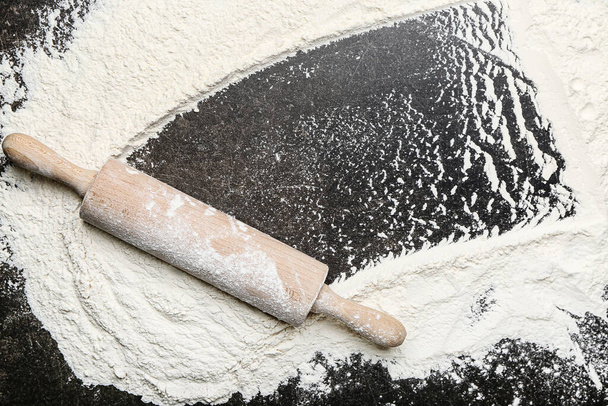 Wooden rolling pin and flour on dark background - 写真・画像