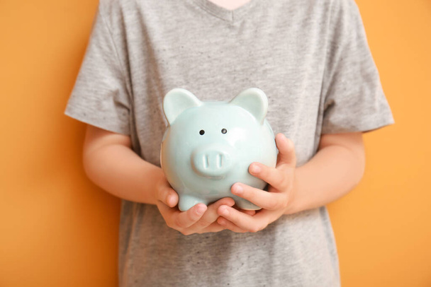 Child holding piggy bank on color background - Foto, immagini