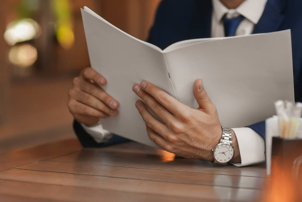 Молодий бізнесмен читає журнал в кафе, крупним планом
 - Фото, зображення