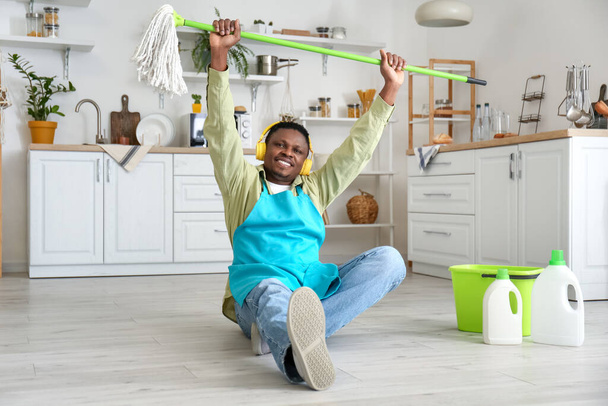 キッチンを掃除しながら音楽を聴くアフリカ系アメリカ人男性 - 写真・画像