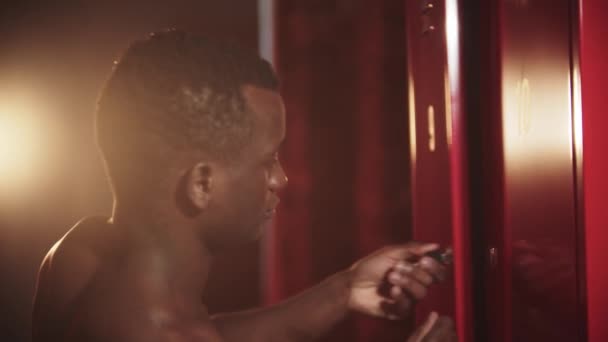Ein schwarzer Mann schließt seinen Spind mit einem Schlüssel in der Umkleidekabine - Filmmaterial, Video