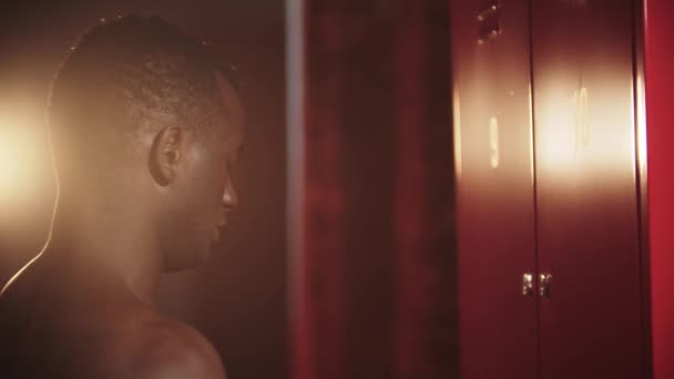 Un hombre negro abriendo su casillero en una llave en el vestuario - Imágenes, Vídeo