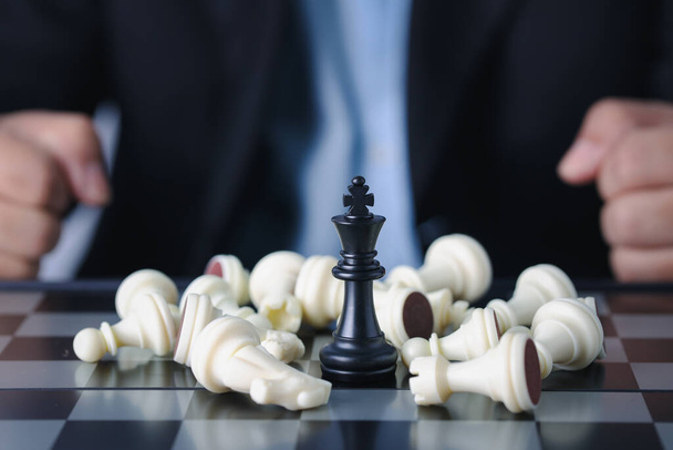 O dedo do empresário controla o rei do xadrez para a posição de sucesso no jogo de negócios da competição com o xadrez inimigo em queda, o significado do planejamento e da decisão estratégica e o conceito do objetivo da conquista. - Foto, Imagem