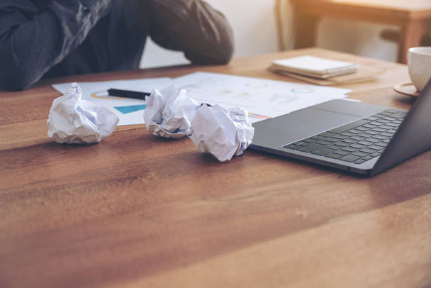 Μια επιχειρηματίας που εργάζεται με αίσθημα σαν αποτυχία και τόνισε με μαντάρα χαρτιά και φορητό υπολογιστή στο γραφείο - Φωτογραφία, εικόνα