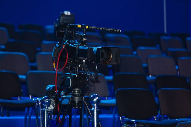 Profesionální kamera, videokamera, černá silueta kamery na modrém pozadí, zblízka - Fotografie, Obrázek