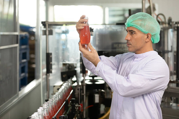mężczyzna fabryka pracownik gospodarstwa czerwony nasiona bazylii napój do sprawdzania jakości w fabryce napojów - Zdjęcie, obraz