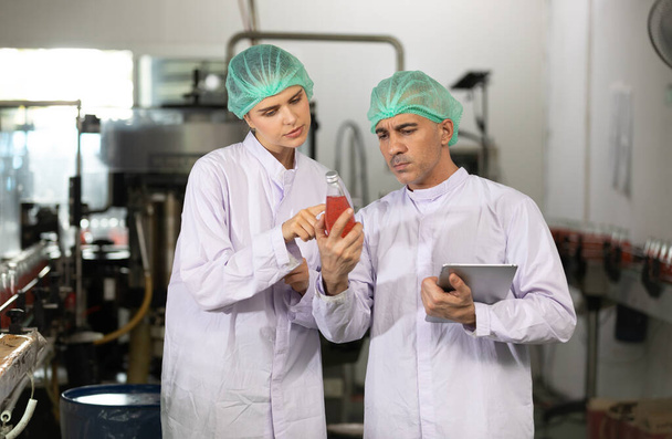 two factory workers talking about project and checking quality of basil seed drink in beverage factory - Photo, Image