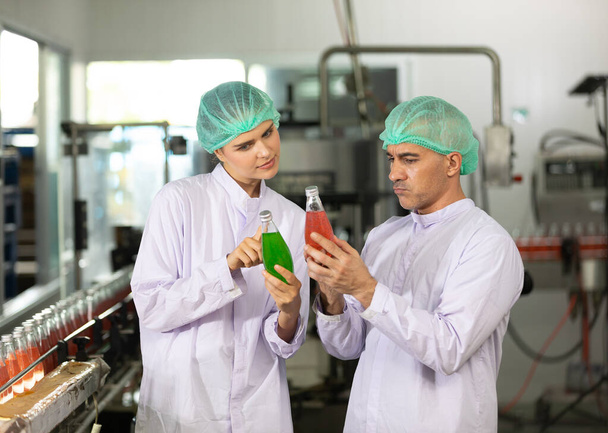 zwei Fabrikarbeiter sprechen über das Projekt und die Qualitätskontrolle des Basilikumsaatgetränks in der Getränkefabrik - Foto, Bild