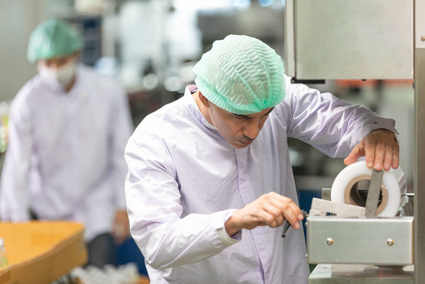 mannelijke fabrieksarbeider controleren rol papier of verpakkingsmachine in de fabriek - Foto, afbeelding