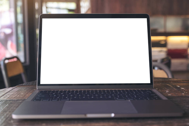 Mockup-Bild von Laptop mit leerem weißen Desktop-Bildschirm auf Holztisch im modernen Café - Foto, Bild