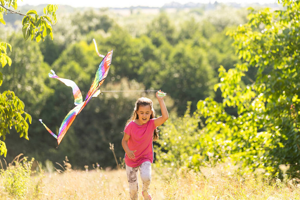 Kleines Mädchen läuft mit einem Drachen im Freien - Foto, Bild