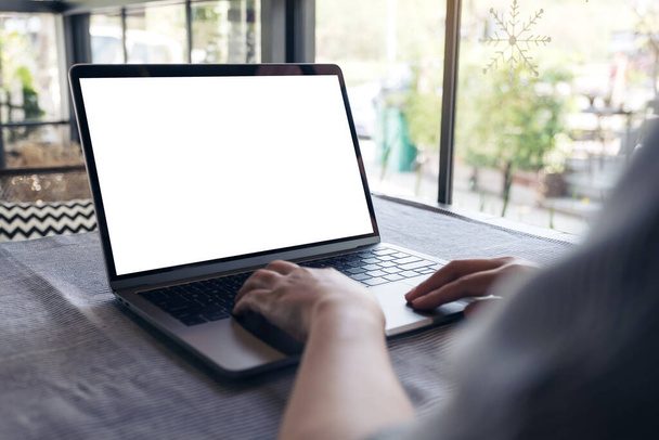 Mockup kép egy kéz segítségével és megható laptop üres fehér asztali képernyőn az asztalon kávézóban - Fotó, kép