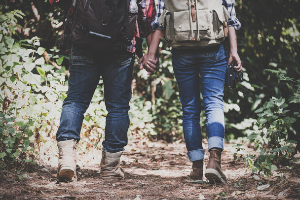 Closeup image of a lover couple holding hands and trekking in a tropical forest together - Zdjęcie, obraz