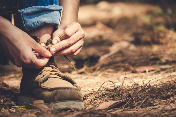 Closeup image of a man tying shoelace while trekking in a tropical forest - Φωτογραφία, εικόνα