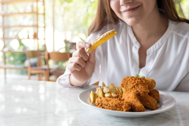 Lähikuva kuva kaunis aasialainen nainen syö ranskalaisia perunoita ja paistettua kanaa ravintolassa - Valokuva, kuva
