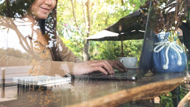 Immagine di primo piano di donna d'affari che lavora e digita sulla tastiera del computer portatile sul tavolo di legno nel caffè  - Foto, immagini