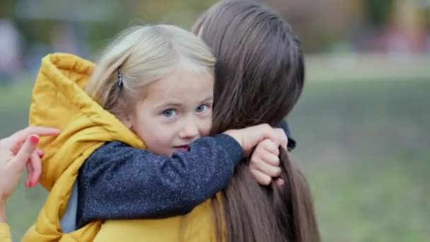 Hija abrazando a la madre en la naturaleza. Hermosa joven y su encantadora hijita se abrazan y sonríen. Hija abrazando madre en la naturaleza. - Imágenes, Vídeo