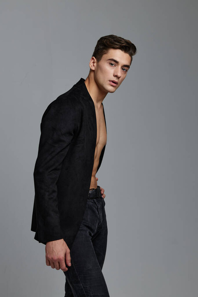 Side view of a man in an unbuttoned jacket and trousers on a gray background - Foto, Imagen