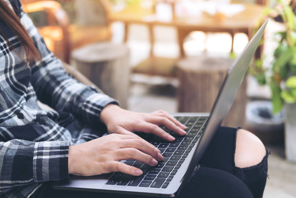 Жінка, яка використовує і друкує на ноутбуці, сидячи на відкритому повітрі з розмитим фоном
  - Фото, зображення