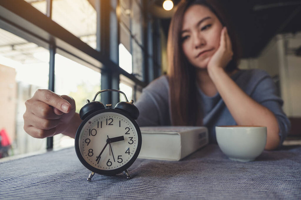 Une femme asiatique pointant vers une horloge noire avec un sentiment d'ennui en attendant quelqu'un - Photo, image