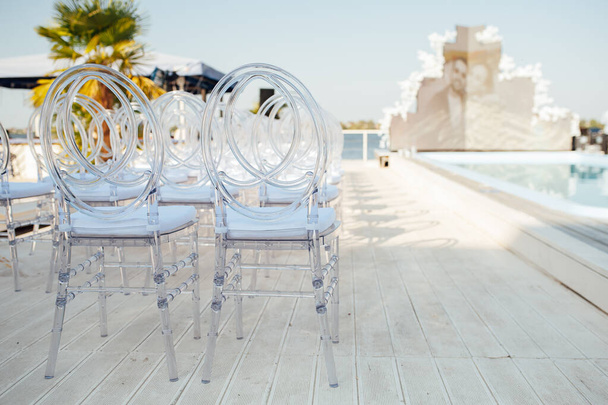 Glass chairs stand in a row in a beautiful wedding outing ceremony - Foto, afbeelding