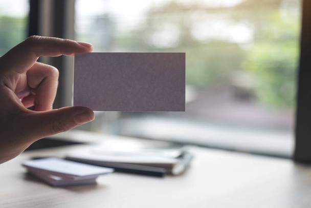 A hand holding and showing an empty business card in office - 写真・画像