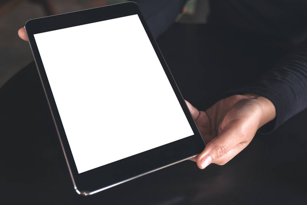Imagen burlona de las manos sosteniendo y mostrando PC tableta negra con pantalla blanca en blanco en la mesa - Foto, Imagen