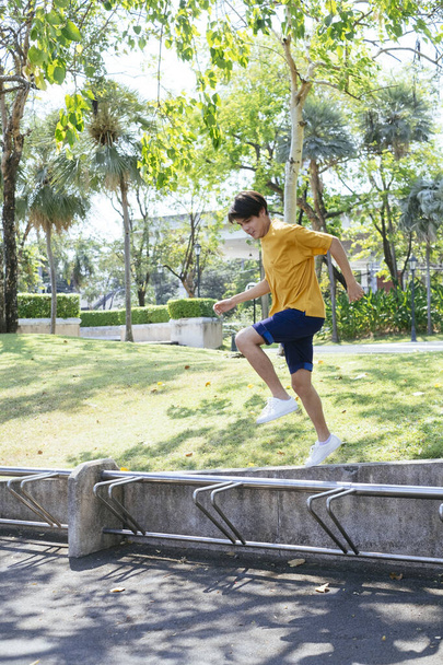 Chłopiec w żółtej koszulce i niebieskich spodniach spędza czas w parku zieleni. - Zdjęcie, obraz