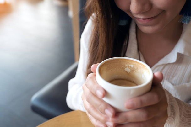 カフェ気分で飲む前にコーヒーカップを持っているアジアの女性のクローズアップイメージ - 写真・画像