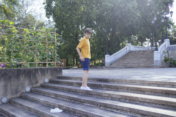 Guy in yellow t-shirt and blue pants walking up the cobblestone stair and leave the shoe behind, horizontal. - Foto, imagen