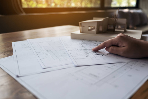 Архитектор, работающий над архитектурной моделью с бумагой на столе - Фото, изображение