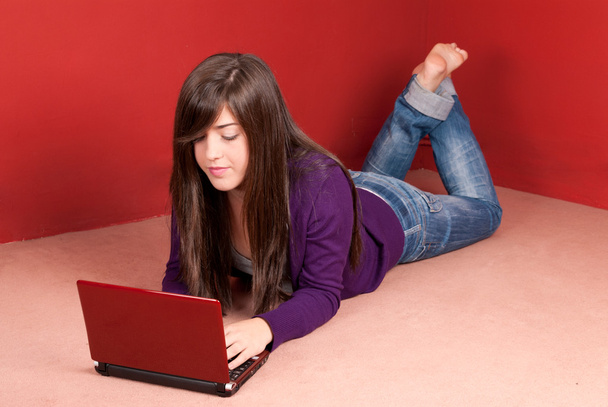 Молодая женщина с ноутбуком лежит на полу дома
 - Фото, изображение