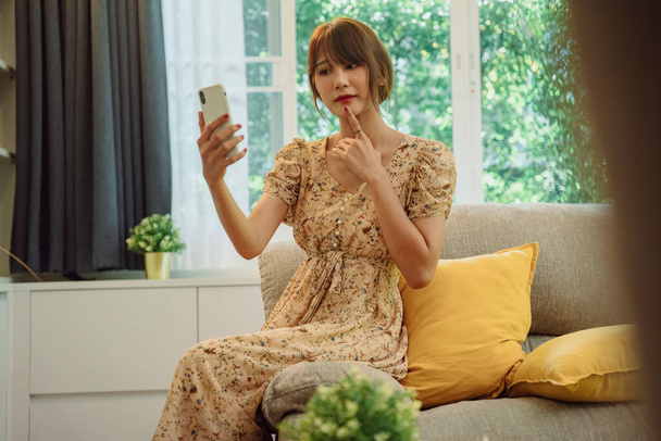 Güzel Asyalı Taylandlı kadın evden online alışveriş için akıllı telefon kullanıyor. Covid-19 salgını. Yeni normal. - Fotoğraf, Görsel