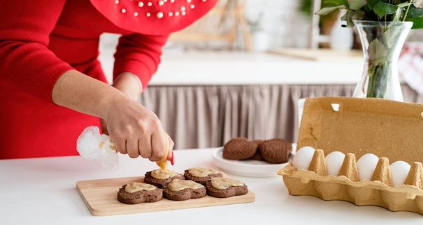 Valentýn. Žena v červených šatech dělat valentýnské sušenky v kuchyni - Fotografie, Obrázek