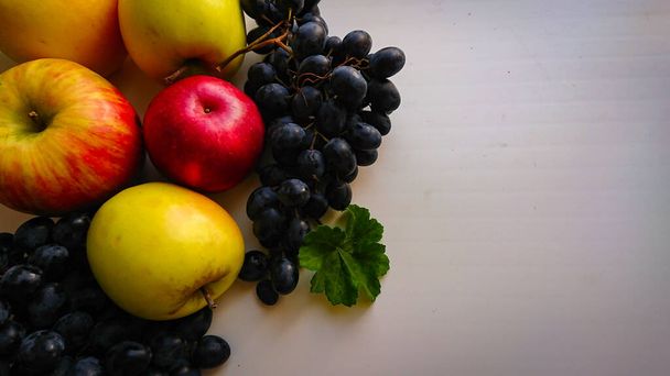Fruits d'automne nature morte. Raisins et pommes sur fond clair avec de la place pour copier - Photo, image